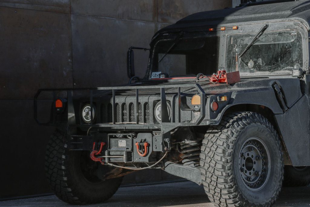 A rugged black 4x4 jeep parked outside with sunlight casting shadows.